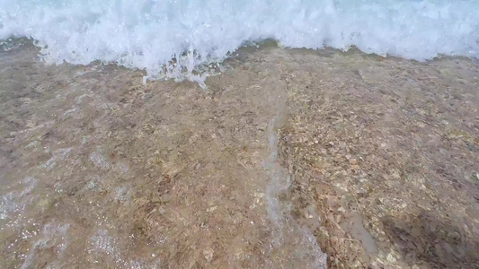 阳光下的海南三亚海棠湾蜈支洲岛海岸线上礁石沙滩海浪玻璃海浪花微距慢镜视频