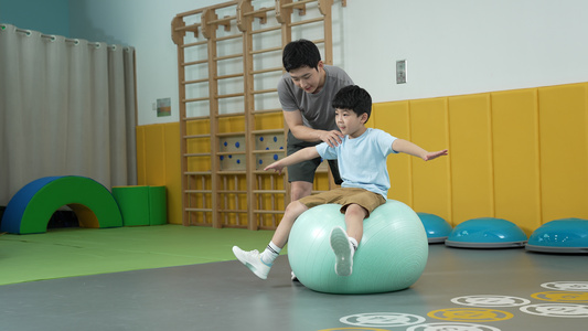 男孩坐在瑜伽球上锻炼平衡能力视频