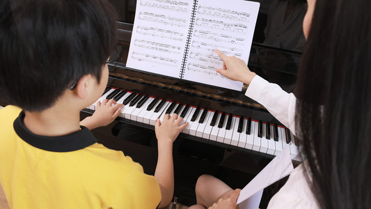 音乐家教指导男孩弹奏钢琴视频