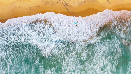 4K航拍海南万宁海滩边手拿冲浪板的运动员视频