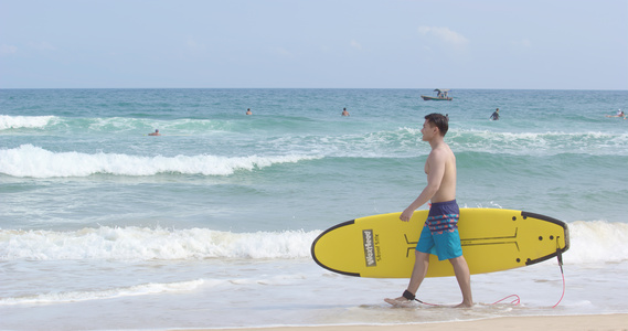 8K男青年海边抱着冲浪板行走[滑水板]视频