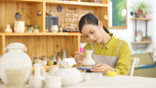 4k陶器店陶艺DIY女生正在给陶器陶罐上色视频