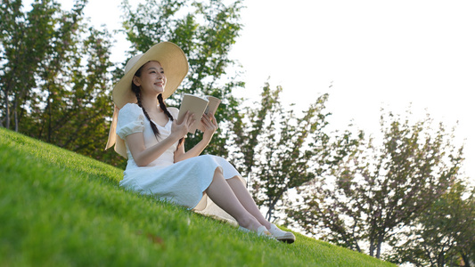 白色长裙女孩在草地上看书视频