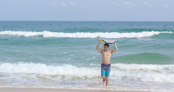 8K海边男青年手举冲浪板视频