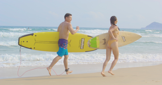 8K海边拿着冲浪板嬉戏的泳装情侣视频