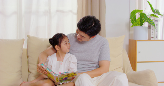 8K爸爸陪女儿坐在沙发上看故事书视频