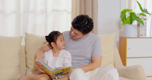 8K爸爸陪女儿坐在沙发上看故事书11秒视频