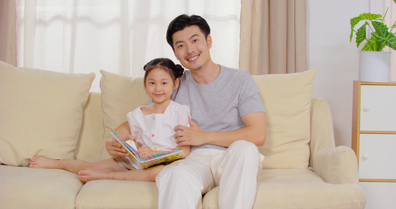8K爸爸陪女儿坐在沙发上看故事书视频