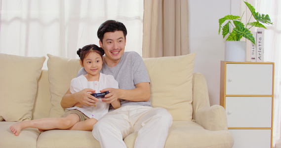 8K爸爸陪女儿坐在沙发上玩游戏视频