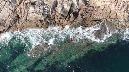 俯拍蓝色海洋海浪拍打礁石视频