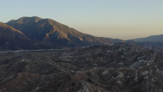 空中:飞越加利福尼亚农村地区,日落4公里时有公路和山丘视频