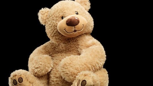 大棕褐色泰迪熊带着微笑在黑色背景上旋转孩子玩具视频