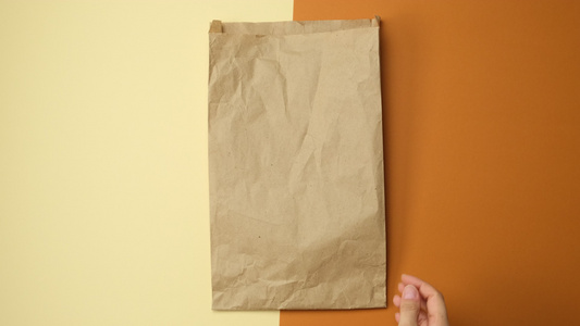 两只手拿着一纸袋棕褐色的Kraft纸在棕色背景上视频