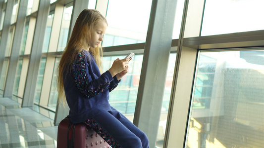 在机场的可爱小女孩靠近大窗边玩手机的小小姑娘视频