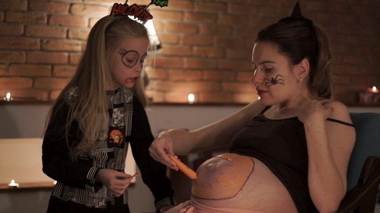 怀孕母亲和女儿在她的肚子里拉着颜料在她那神圣的夜晚视频