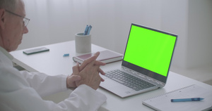 男性医生正在网上咨询在诊所办公室看笔记本电脑绿色屏幕15秒视频
