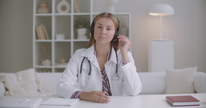年轻女医生正在用耳机监听病人或同事的耳机使用视频电话16秒视频