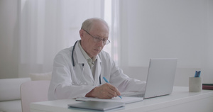 男性医生正在阅读关于笔记本屏幕的科学文章为教育和高级16秒视频