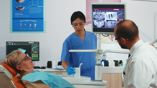 医生用数字屏幕指着显示牙科植入器的数字屏幕视频