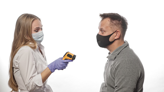 使用戴着医用口罩的非接触式温度计护士测量患者或员工视频