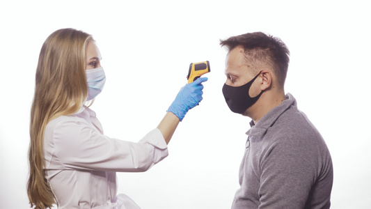 戴着医用口罩的护士使用非接触式温度计测量患者或员工视频