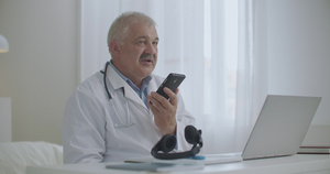 男医生在诊所办公室用免提电话说话沟通病情17秒视频