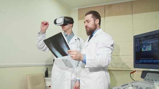 使用3DVR眼镜的医生而他的同事检查一名病人的X光视频