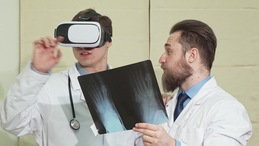 男医生戴副眼镜他的同事检查一名病人的X光视频