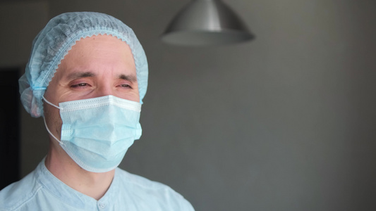 一名男性医生在病期间戴保护面罩疲惫的医生倾听视频