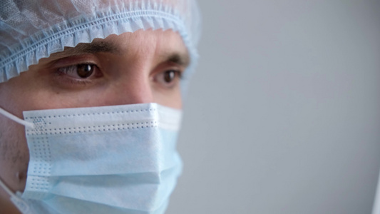 一位在大流行期间戴着防护面具的男医生他移开视线避开视频