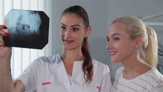 女牙医向牙医内阁的病人展示X光照片b视频