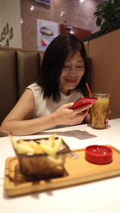 一个女人在餐厅吃饭时使用手机视频