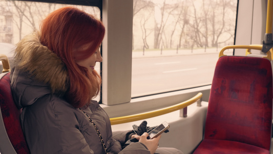 美丽快乐的女孩在公共交通中使用智能手机视频