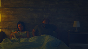 丈夫要睡觉时妇女在夜灯前在床上看一本书12秒视频