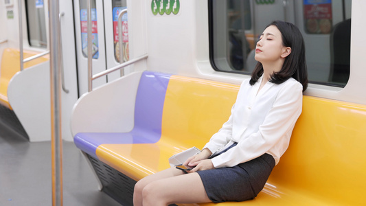 女孩坐地铁玩手机累后闭眼休息视频