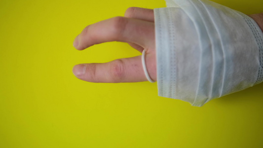 保护性医用口罩缠绕在手臂上背景是黄色的带有艺术涂料视频