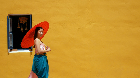 身穿泰国传统服装的泰籍妇女红色复古雨伞在背景上与黄色视频