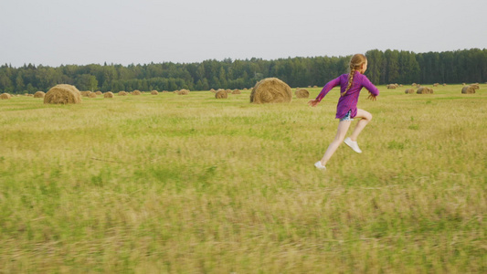 可爱女孩经营乡村田地干草堆夏季风景视频