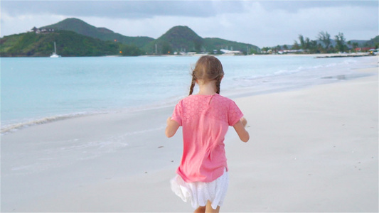 日落时小女孩在海滩上行走的轮廓视频