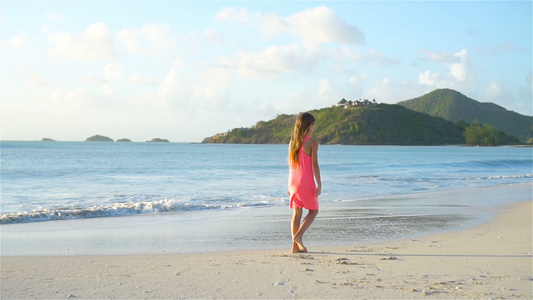 日落时小女孩在海滩上行走的轮廓视频