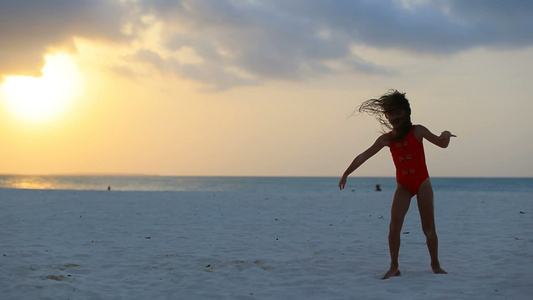 日落时在白沙滩上可爱活跃的小女孩的休眠视频