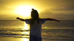 日落时在白色沙滩上快乐的小女孩美丽的日落海岸上9秒视频