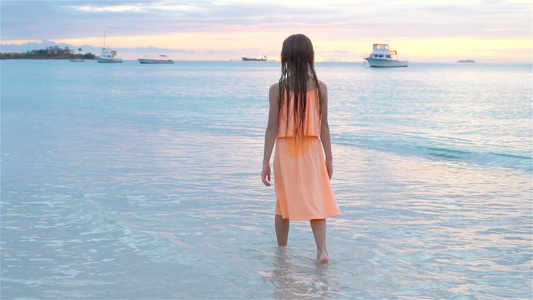 日落时在白沙滩散步的可爱快乐小女孩慢动作视频视频