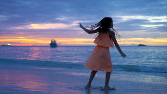 小女孩在日落时在海滩跳舞的休戚与共视频