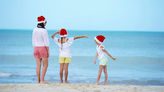 圣诞假期间在白沙滩上戴着圣诞节帽子的家庭视频