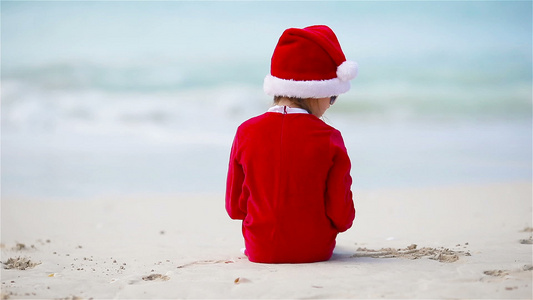 圣诞假时在白沙滩上穿着圣诞帽的可爱女孩的背影视频