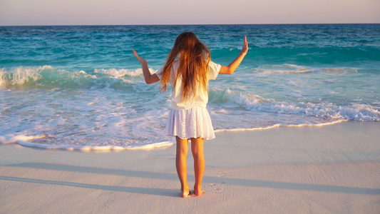 可爱的快乐小女孩在热带海滩日落时在黄昏视频