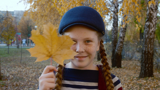 快乐的女孩在公园里拿着叶子和斜眼视频