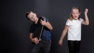 小男孩假装用滑板弹吉他姐姐或朋友女孩在他旁边跳舞在7秒视频