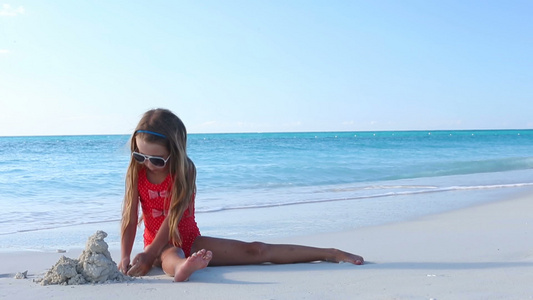 可爱的小女孩在热带沙滩上造沙子城堡视频